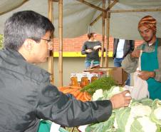 O feirante Felipe Oliveira cuida da banca de verduras, legumes, vegetais e frutas