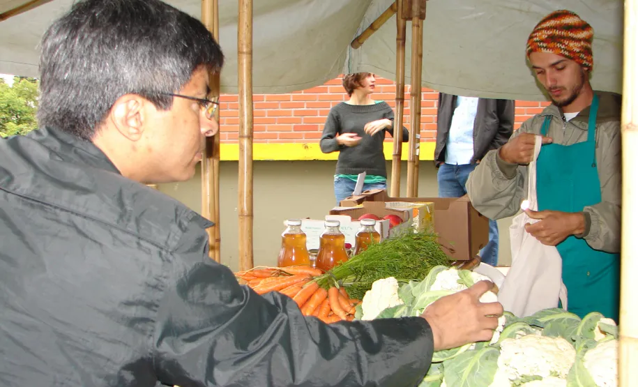 O feirante Felipe Oliveira cuida da banca de verduras, legumes, vegetais e frutas