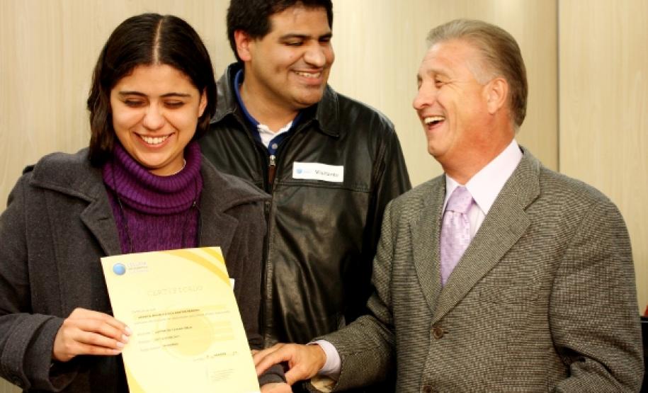 O presidente da Celepar, Jacson Carvalho Leite, ao lado do professor Ricardo José de Lima, entrega o certificado de conclusão de curso à assistente administrativo Géssica Pereira